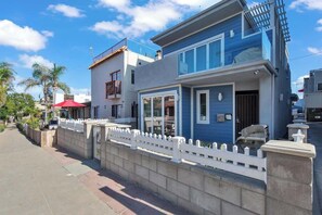 A modern two-story house with a balcony, a garage, and a white picket fence.
