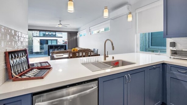 A modern kitchen with a dishwasher, sink, and a set of knives in a box.