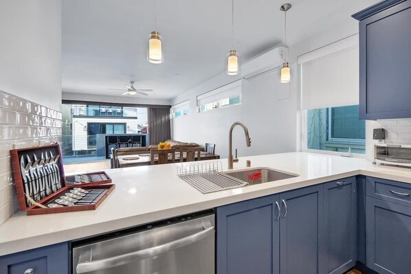 A modern kitchen with a dishwasher, sink, and a set of knives in a box.