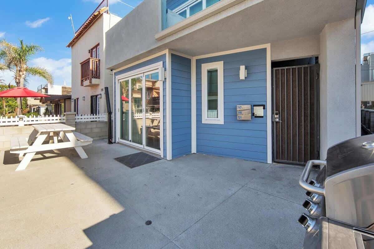 A building with a blue exterior, a sliding glass door, a picnic table, and a barbecue grill.