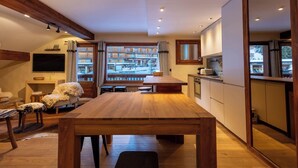 Una cocina moderna con una mesa y un banco de madera, un televisor montado en la pared y vistas a la calle.