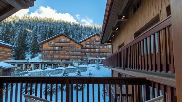 Un edificio de madera con balcones que dan a una zona montañosa nevada.