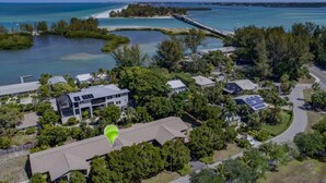 An aerial view of a coastal residential area with houses, a dock, and clear blue waters. - Beautifully renovated Longboat Key Villa brief walk to a private beach (Longboat Key)