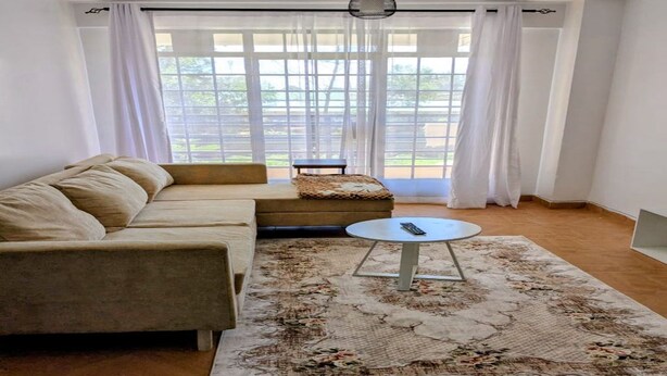 Ein Wohnzimmer mit einem beigen Sofa, einem runden Couchtisch und einem gemusterten Teppich.