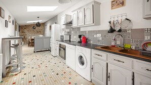 Une cuisine moderne avec des meubles blancs, un lave-linge, un four à micro-ondes et un évier.