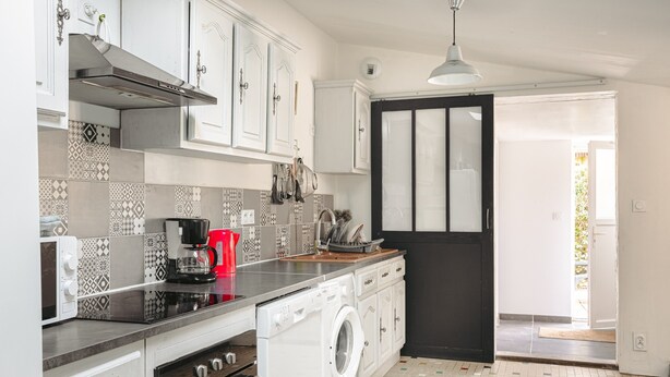 Une cuisine équipée d’un lave-linge, d’une machine à café et d’une porte noire.
