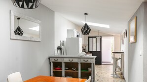 Un coin repas comprenant une table en bois, des chaises, un buffet blanc et un luminaire suspendu.