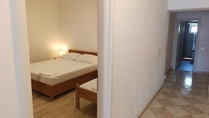 A bedroom with a wooden bed, a bedside table, and a nightstand with a lamp. - Seafront Apartment Valla 5 (Novalja)