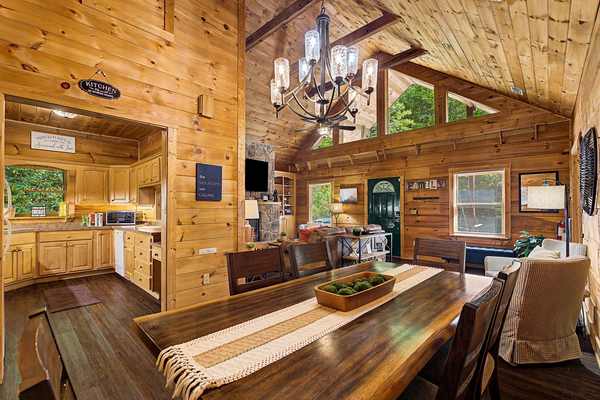 A wooden cabin interior with a kitchen, dining area, and a living room.