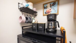 A kitchen with a coffee maker, tea and coffee containers, and a hanging rack with cups. - Full clean 3-bedroom house close to stadiums and pet friendly! (Grandview)