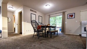 A dining area with a carpeted floor, a table, four chairs, and a window with a view of greenery. - Full clean 3-bedroom house close to stadiums and pet friendly! (Grandview)