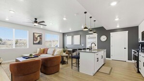 A modern living room with a sofa, ottomans, and a dining area with a kitchen island. - Sand Yeti Brand New Listing! (Hurricane)