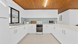 Una cocina moderna con armarios blancos, techo de madera y salpicadero de azulejos.