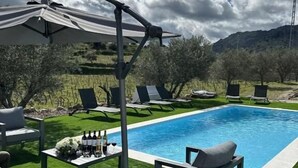 Ein Swimmingpool mit Pergola, Liegestühlen und einem Tisch mit Flaschen und Gläsern.