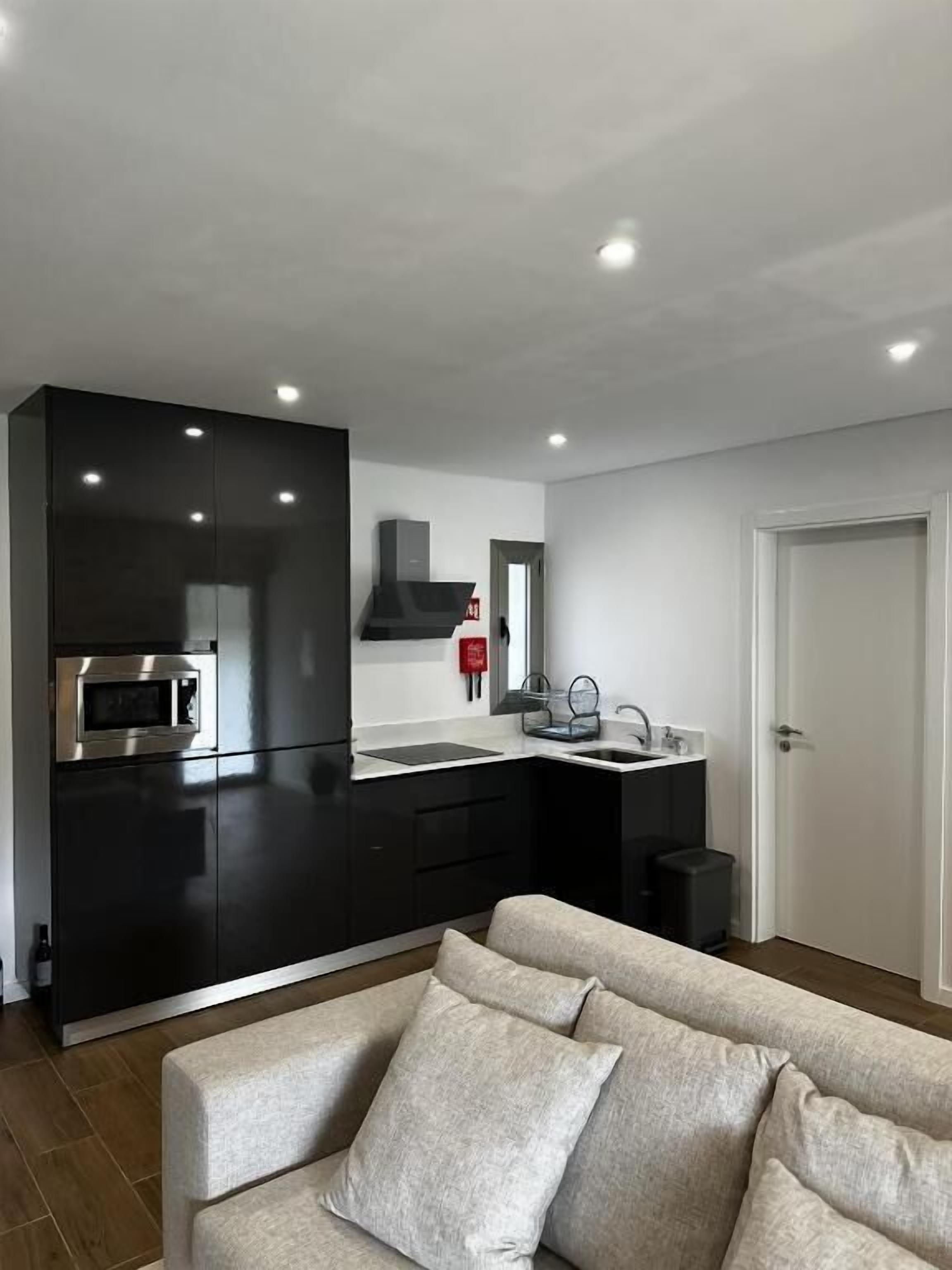 A modern kitchen with black cabinets, a stainless steel microwave, and a built-in oven.