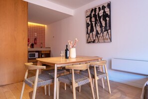 A dining area with a wooden table and chairs, a vase with flowers, and a painting on the wall. - Garça Real - Porto House w/Terrace by Lisbeyond (Porto)