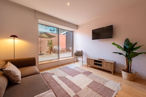 A modern living room with a sofa, a flat-screen TV, a large window, and a potted plant. - Garça Real - Porto House w/Terrace by Lisbeyond (Porto)