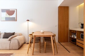 A compact living space with a dining table, a sofa, a floor lamp, and a kitchenette. - Garça Real - Porto Retreat by Lisbeyond (Porto)