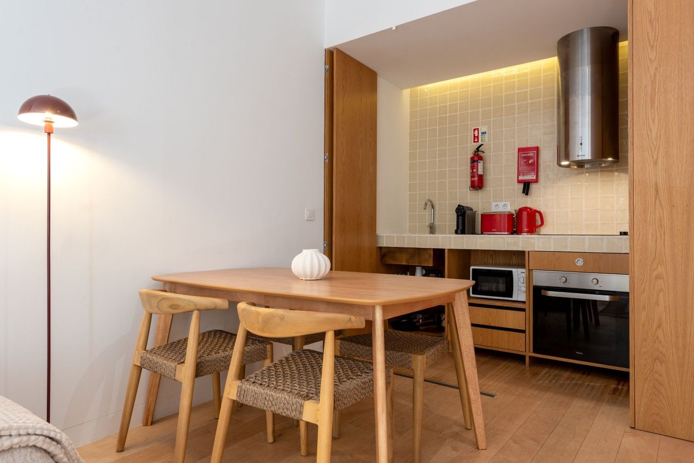 A compact kitchen with a wooden table and chairs, a microwave, oven, and a gas stove.