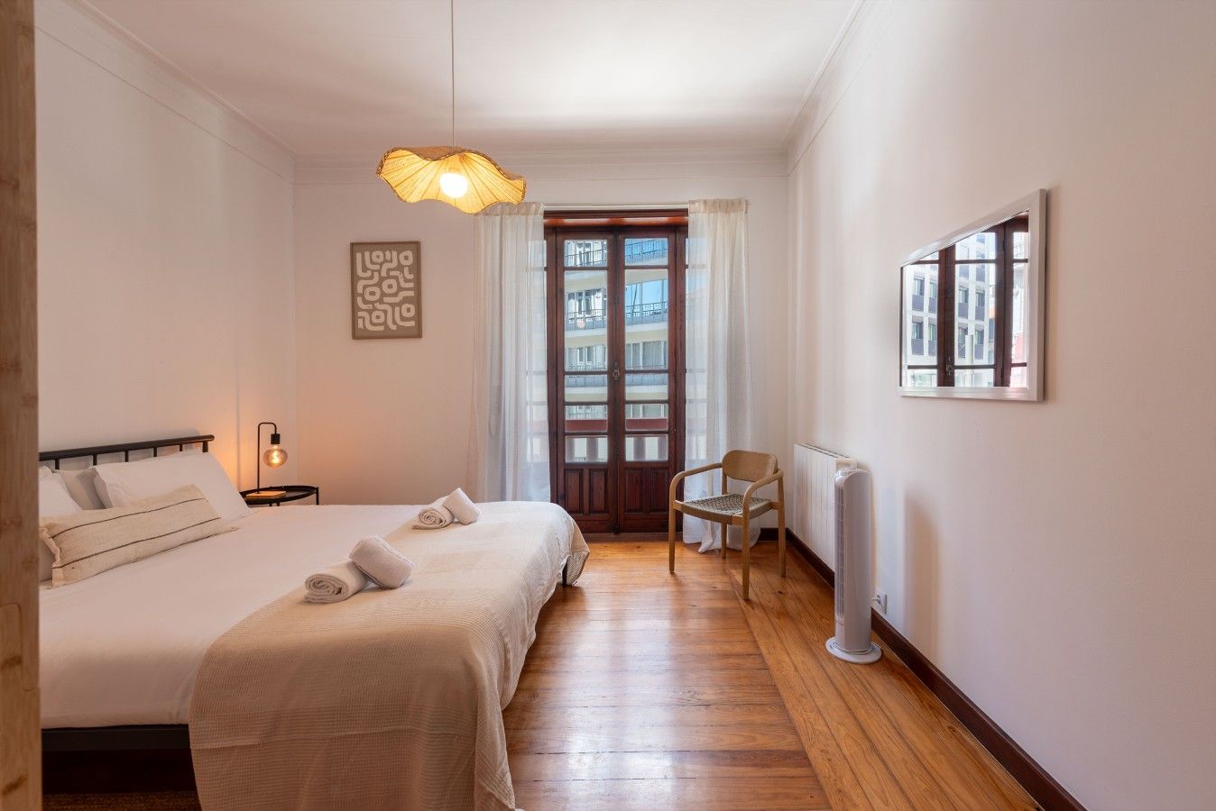 A hotel room with a bed, a chair, a radiator, and a door leading to an outdoor area.