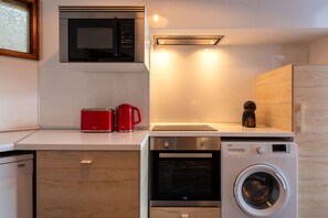 A compact kitchen with a microwave, toaster, coffee maker, and a washing machine. - Garça Real - Porto Group Apartment by Lisbeyond (Porto)