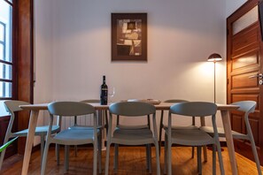 A dining area with a table, four chairs, a wine bottle, and a framed picture on the wall. - Garça Real - Porto Group Apartment by Lisbeyond (Porto)