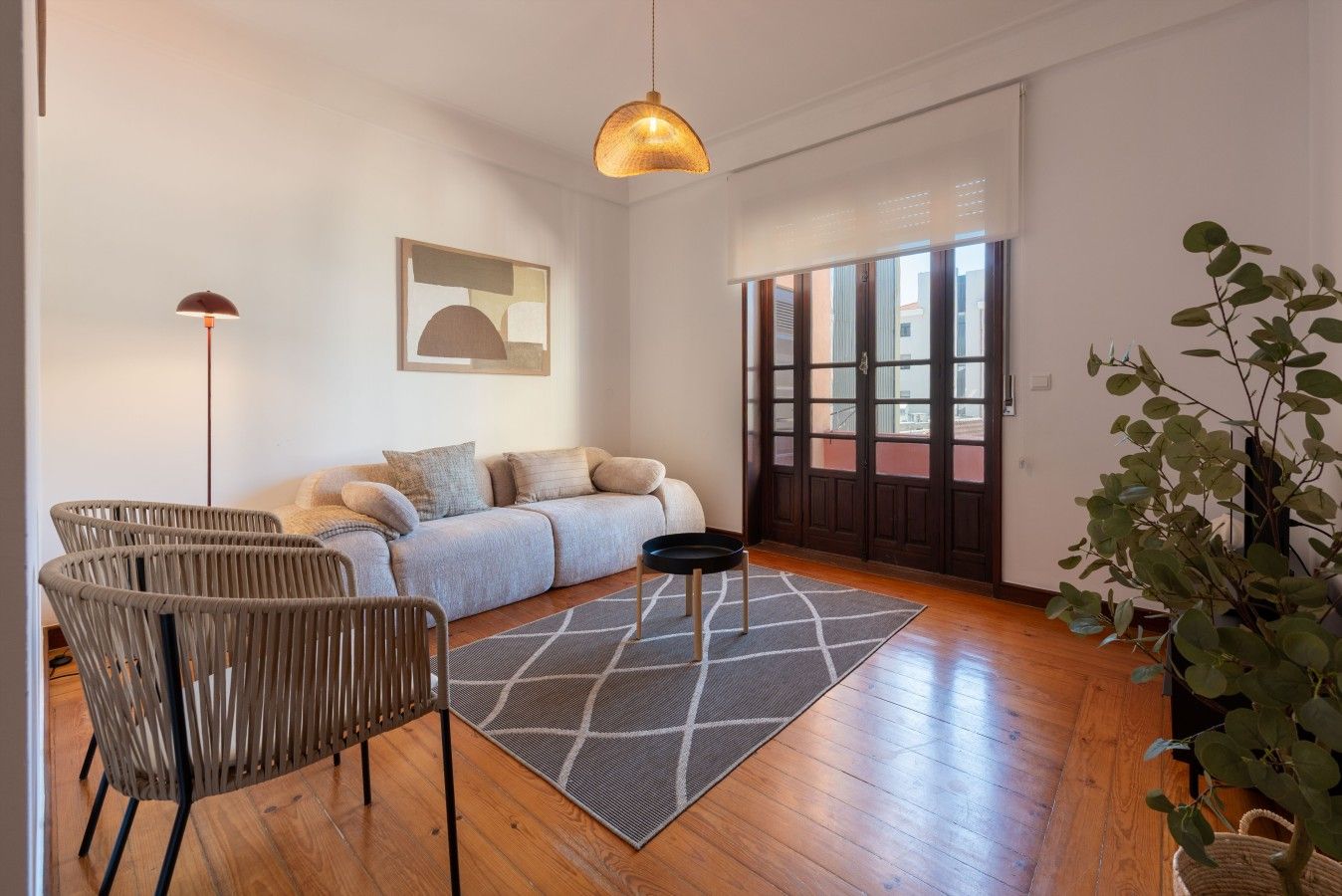 Uma sala de estar moderna com um sofá, cadeiras, um tapete e um lustre.