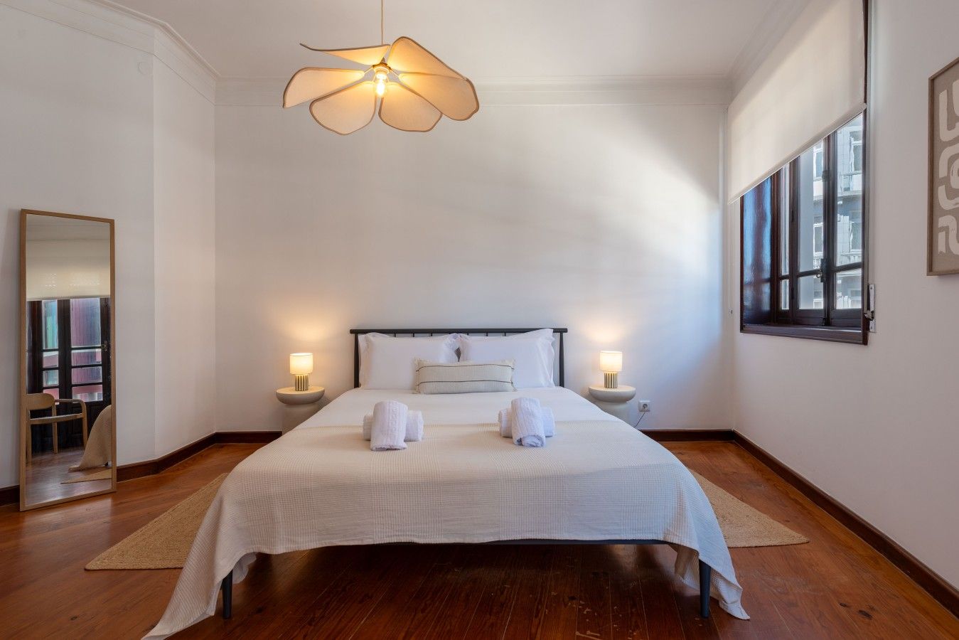 Ein Hotelzimmer mit einem großen Bett, zwei Nachttischen mit Lampen, einem Deckenventilator und einem großen Fenster.