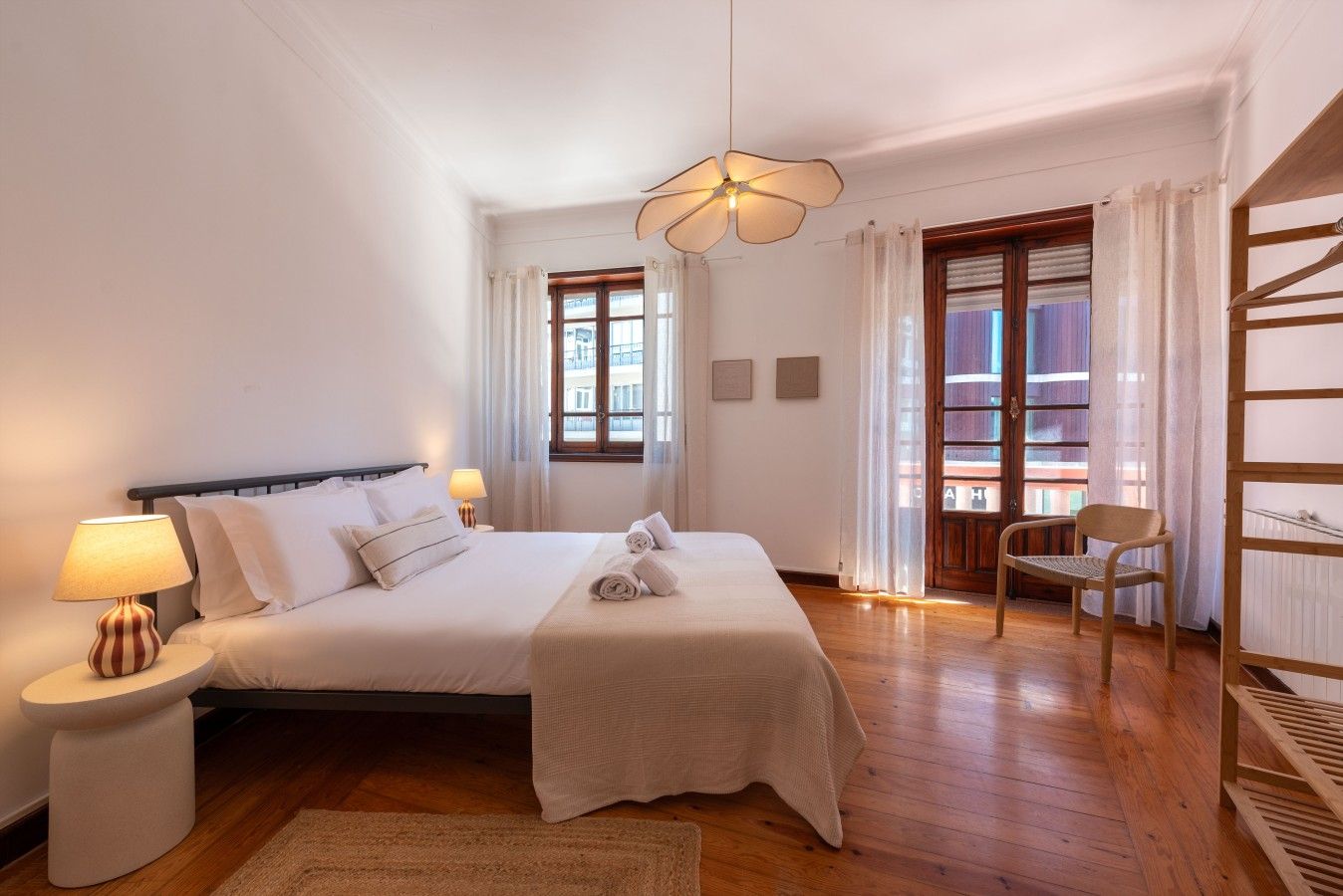 A hotel room with a bed, two bedside tables, a lamp, a window, and a view of the outside.