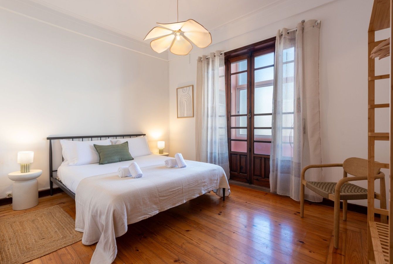 A bedroom with a bed, bedside tables, a chair, and a window with curtains.
