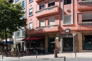 Ein rosafarbenes Gebäude mit Café im Erdgeschoss, Außenbereich und einem verschlossenen Eingang.