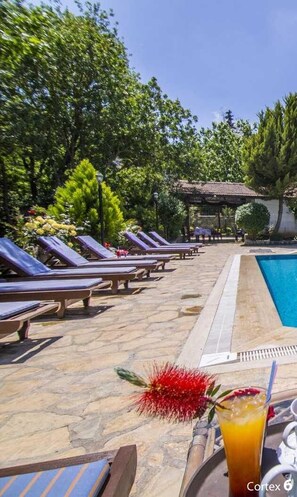 A poolside area with lounge chairs and a clear blue pool. - Authentic One-Bedroom Stone Villa | Luxury Design (Kayaköy)