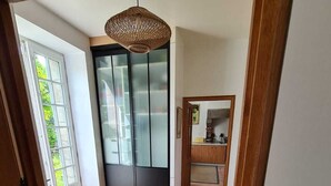 Een modern interieur met een houten vloer, een glazen deur naar een balkon en een keuken met houten keukenkastjes en een hanglamp.