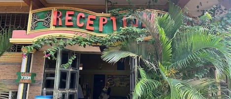 Un bâtiment sur lequel on peut lire l’inscription « RÉCEPTION OASIS » et un panneau indiquant « LAVEZ-VOUS LES MAINS ».
