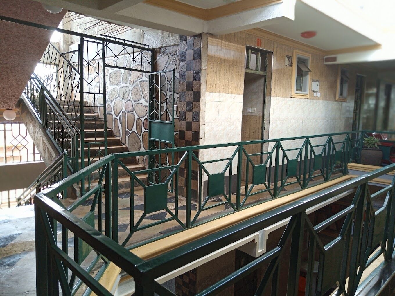 A staircase with a green metal railing leading to a landing.