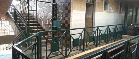 A staircase with a green metal railing leading to a landing.