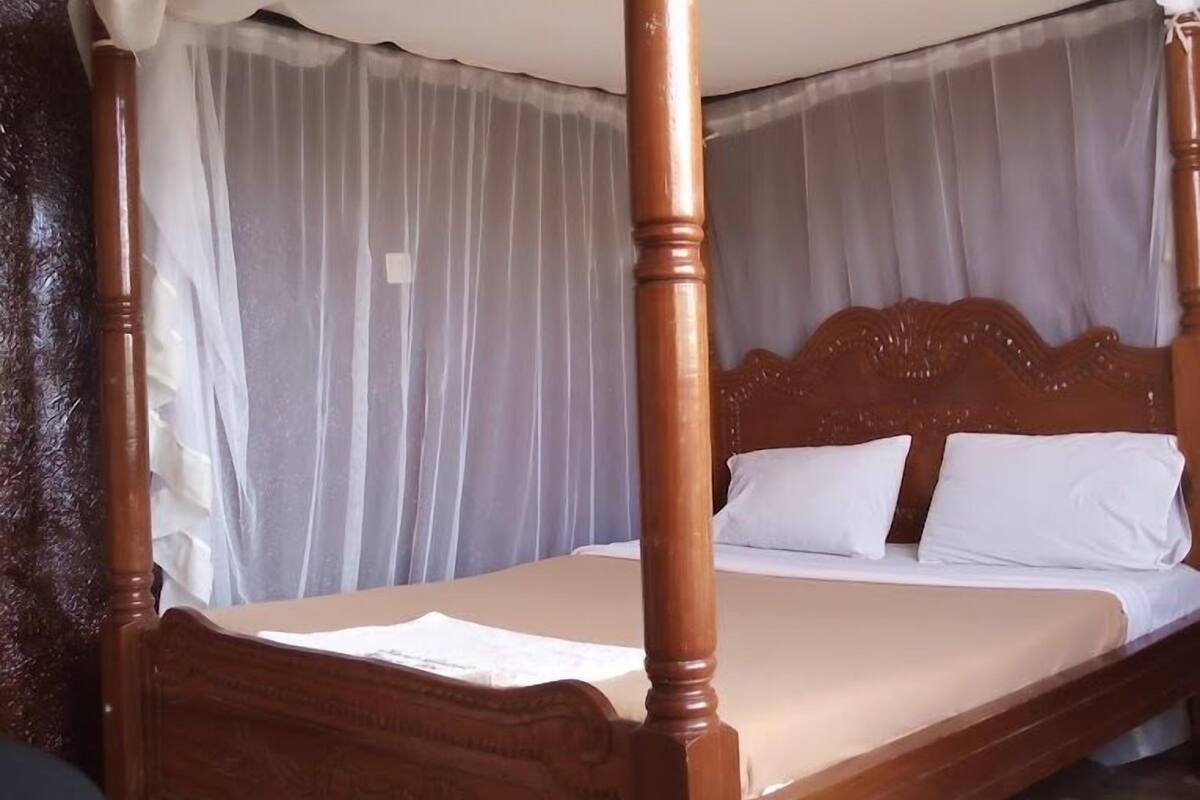 A four-poster canopy bed with a wooden frame and white bedding.