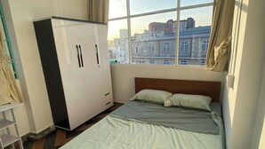 Ein Schlafzimmer mit Bett, Kleiderschrank und Fenster mit Stadtblick.
