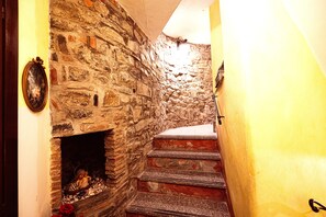A narrow stone staircase leading to a fireplace with a statue, in a room with yellow walls.