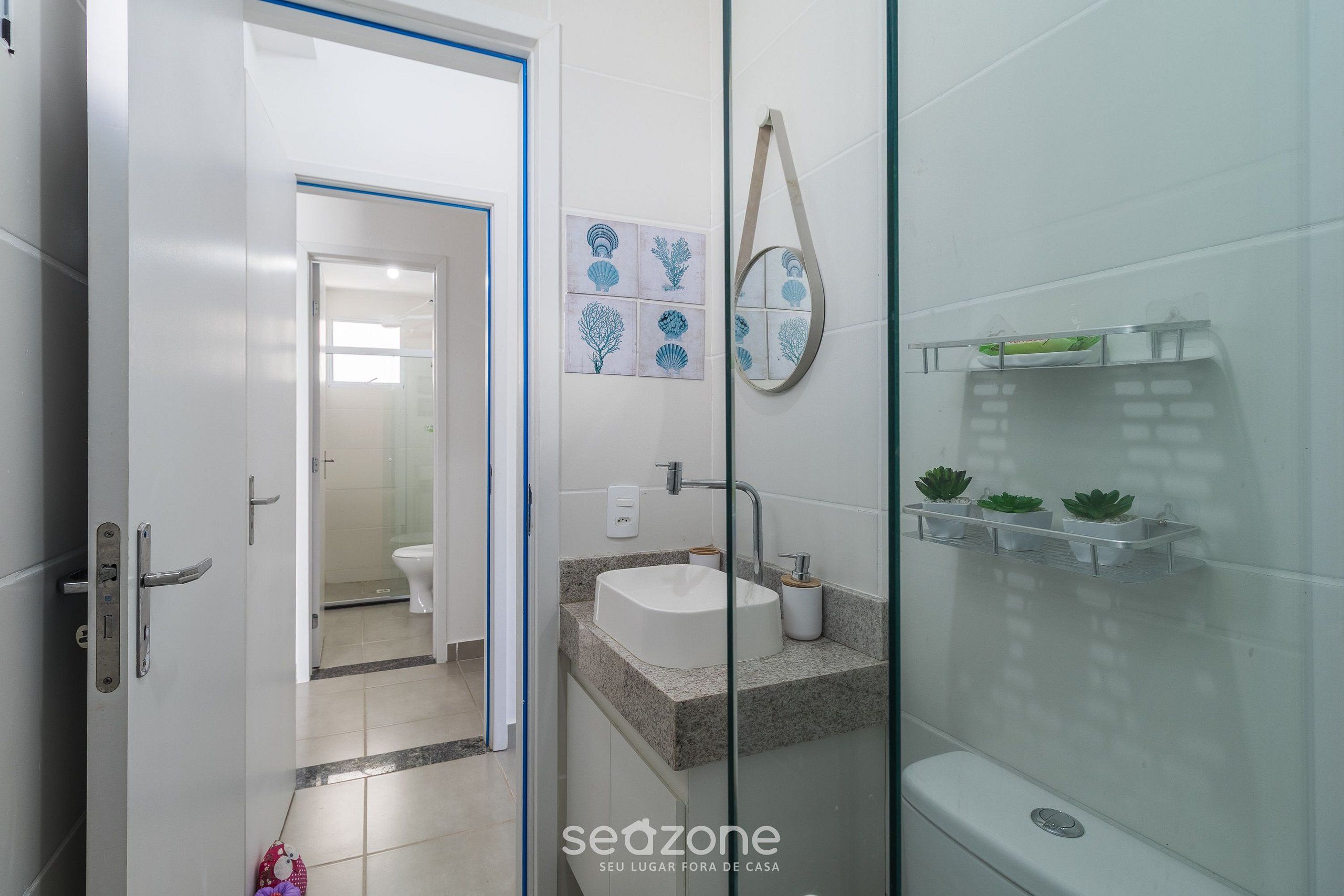 A bathroom with a glass shower enclosure, a sink with a marble countertop, and a toilet.