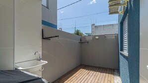 A small, enclosed outdoor shower area with a wooden deck, a white sink, and a towel rack. - Apt in Condo w/ Pool in Porto Seguro Tmr0104 (Porto Seguro)