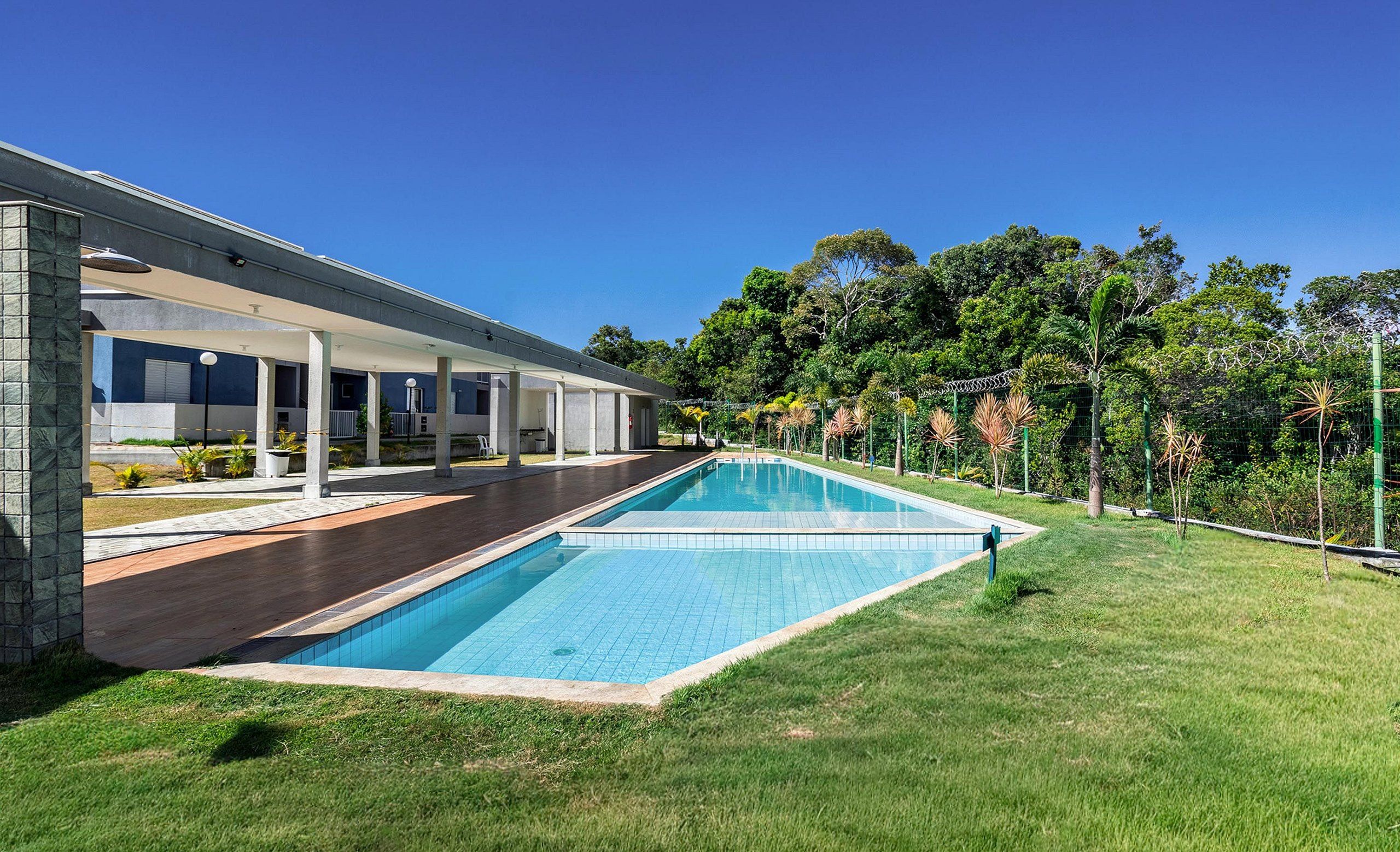 A modern house with a swimming pool, covered patio, and lush greenery.