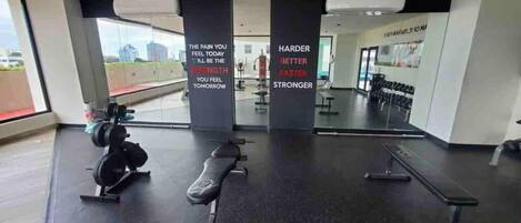 A gym with weightlifting equipment, benches, and motivational quotes on the walls.