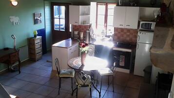 Une cuisine compacte avec des meubles blancs, une table à manger avec des chaises, un petit réfrigérateur et un four à micro-ondes.