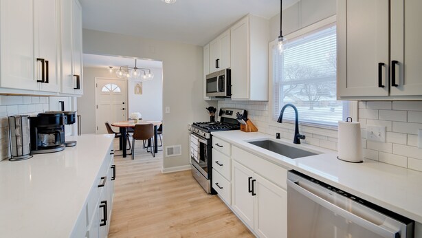 A modern kitchen with white cabinetry, a stainless steel dishwasher, and a built-in microwave. - Remodeled Home w/ Garage, Workspace & Fenced Yard (Racine)