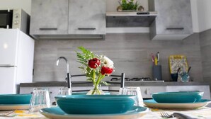 Una cocina moderna con armarios grises, un lavamanos de acero inoxidable y un florero con rosas rojas en la encimera.