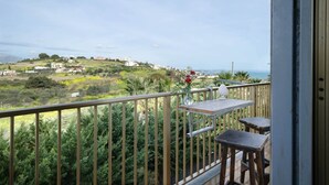 Un balcón con vistas a un paisaje montañoso y al mar.