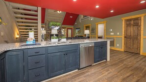 A kitchen with dark blue cabinets, a stainless steel dishwasher, and a red ceiling. - Smoky Mountain Plunge (Gatlinburg)