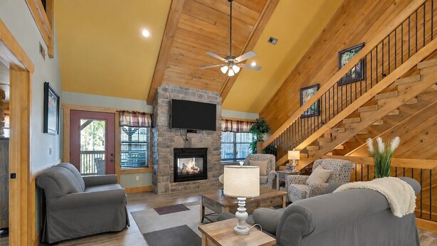 A spacious living room with a stone fireplace, wooden ceiling, and a staircase. - Splash Mountain Lodge (Gatlinburg)