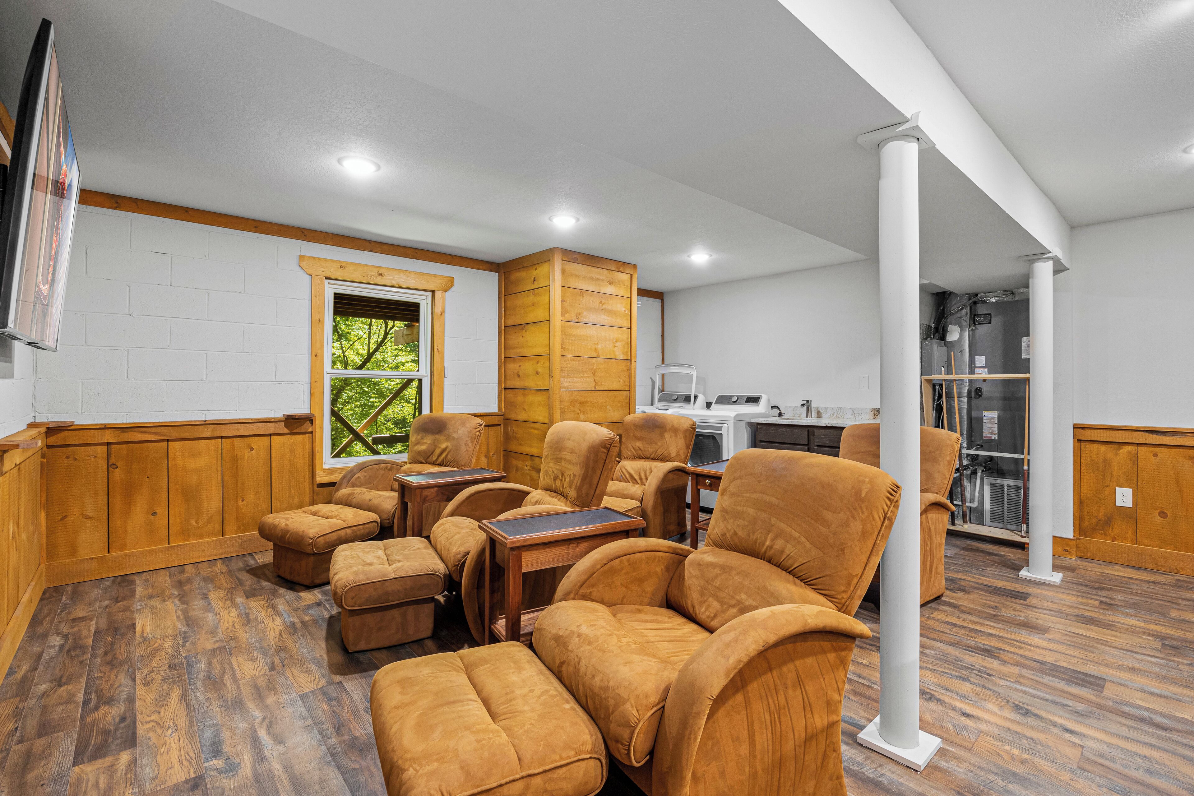 Una habitación amplia con piso de madera, un ventanal grande y una cocina al fondo.